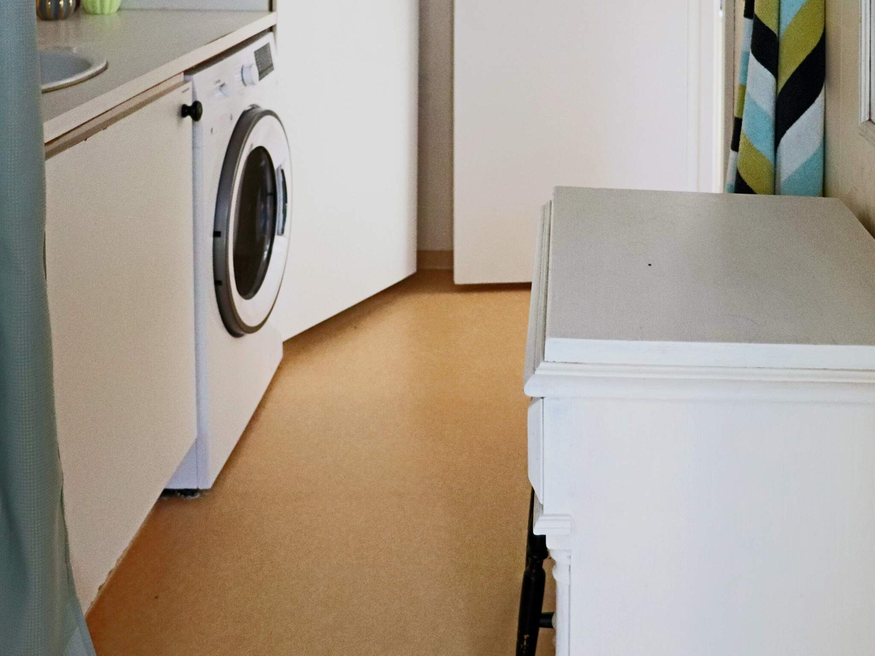 Un área de lavandería con lavadora, secadora y una encimera con lavabo.