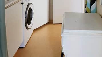 Un área de lavandería con lavadora, secadora y una encimera con lavabo.