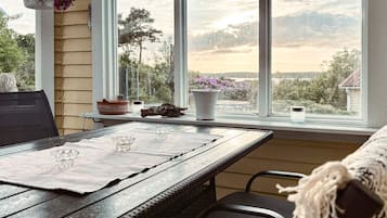 Una mesa de comedor con un mantel individual, una silla y una ventana que ofrece vistas a árboles y montañas.