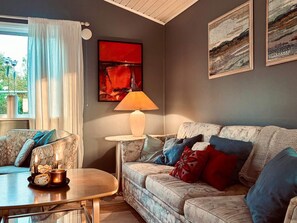 A living room with a sofa, a coffee table, a lamp, and two paintings on the wall. - 4 Star Holiday Home in Varberg (Varberg)