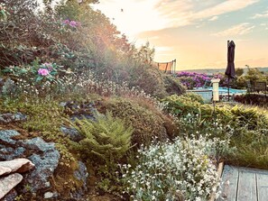 A garden with various plants and flowers, a wooden deck, and a pool area. - 4 Star Holiday Home in Varberg (Varberg)