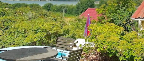 A patio with a round table and chairs, a small pool, and a view of a lake and hills.