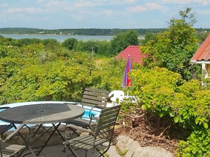 Un patio con una mesa y sillas redondas, una piscina pequeña y vistas a un lago y colinas.