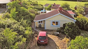 A single-story house with a red roof, surrounded by lush greenery and a clear view of a lake. - 4 Star Holiday Home in Varberg (Varberg)