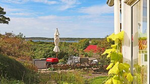 A patio with a grill, outdoor furniture, and a view of a lake. - 4 Star Holiday Home in Varberg (Varberg)