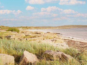 A coastal landscape with large rocks, grassy areas, and a calm sea under a partly cloudy sky. - 4 Star Holiday Home in Varberg (Varberg)