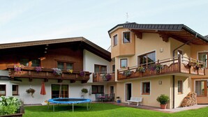 Un edificio a due piani con un balcone, un trampolino e un piccolo giardino.