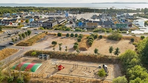 A coastal town with a marina, colorful buildings, and a sandy area with playground equipment. - 7 Person Holiday Home in Ebeltoft (Ebeltoft)