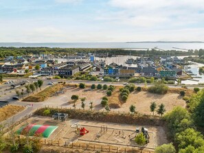 Un pueblo costero con un puerto deportivo, zonas de arena y un parque infantil.