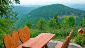 Un tavolo da picnic in legno con panche, immerso in un paesaggio montuoso e boscoso.