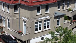 Un edificio a più piani con tetto in tegole rosse e una targa che indica che si tratta di una proprietà residenziale.