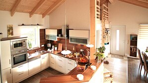 Une cuisine moderne avec des poutres en bois, des appareils en acier inoxydable et un îlot central doté d’un évier et d’un panier à fruits.