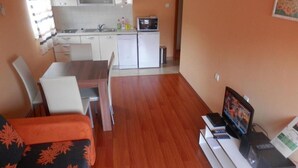 A compact living space with a kitchenette, a dining area, and a seating area with a TV. - Apartments St Rialto - Comfort One-bedroom Apartment With Balcony and Sea View (Jelsa)