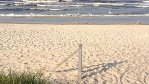 A sandy beach with waves, a wooden post, and some grass. - 55, Apartment House "bel-vital" (Binz)