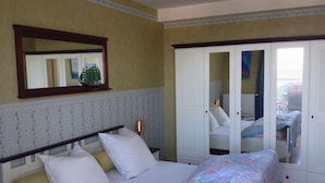 A bedroom with a bed, a nightstand, a lamp, a wardrobe, and a window with a view of the outside. - 55, Apartment House "bel-vital" (Binz)