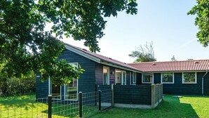 A single-story house with a dark exterior, a red roof, and a fenced yard. - 4 Person Holiday Home in Ulfborg (Ulfborg)
