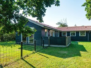 A single-story house with a dark exterior, a red roof, and a fenced yard. - 4 Person Holiday Home in Ulfborg (Ulfborg)