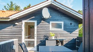 A wooden cabin with a deck, a table, and chairs. - 4 Person Holiday Home in Ulfborg (Ulfborg)
