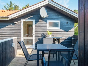 A wooden cabin with a deck, a table, and chairs. - 4 Person Holiday Home in Ulfborg (Ulfborg)