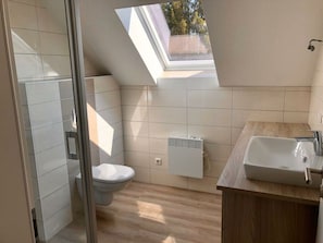 A modern bathroom with a skylight, a toilet, a sink, and a heater. - A gem of a Modern Retreat (Oberharz am Brocken)