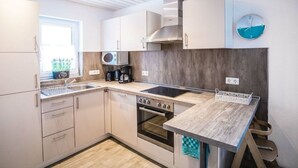 A modern kitchen with white cabinets, a wooden countertop, a built-in oven, and a microwave. - A gem of a Modern Retreat (Oberharz am Brocken)