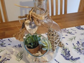Una bottiglia di vetro con decorazioni rustiche, un piccolo vaso di vetro con piante e un ornamento intrecciato.