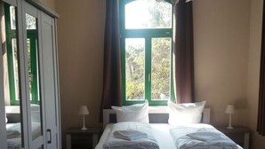 A bedroom with a bed, bedside lamps, a window with curtains, and a wardrobe. - Apartment 1 in an Art Nouveau Villa (Wernigerode)