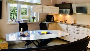 A modern kitchen with white cabinets, a black countertop, and a dining table with chairs.