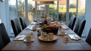 A dining table set for breakfast with a view of the outdoors through large windows. - Residence Island Pearl (Langeoog)