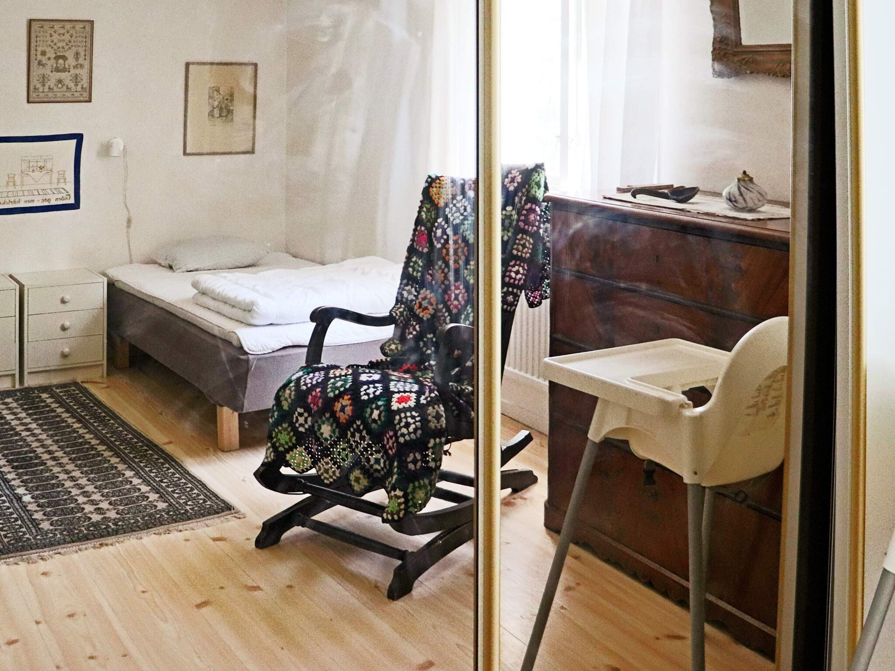 A bedroom with a bed, a chair, a desk, and a small table.