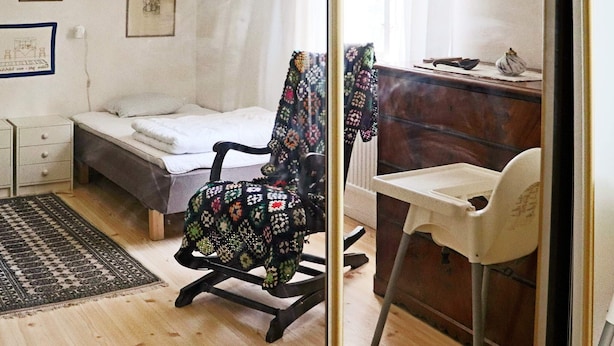Quarto com cama, cadeira, escrivaninha e mesa pequena.