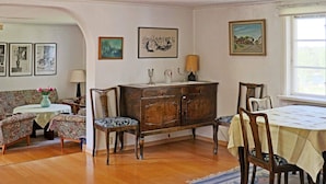 Uma área de refeições com mesa de madeira, cadeiras, um sofá e um armário.
