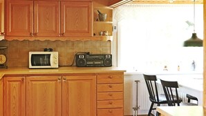 Uma cozinha com armários de madeira, micro-ondas, rádio e janela com vista.