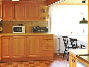 A kitchen with wooden cabinets, a microwave, a radio, and a window with a view. - 4 Star Holiday Home in Langaryd (Långaryd)