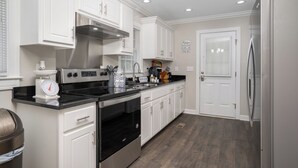 A modern kitchen with white cabinets, stainless steel appliances, and a black countertop. - Modern Home In PRIME location - King Bed/ Spacious

 (Rocky Mount)