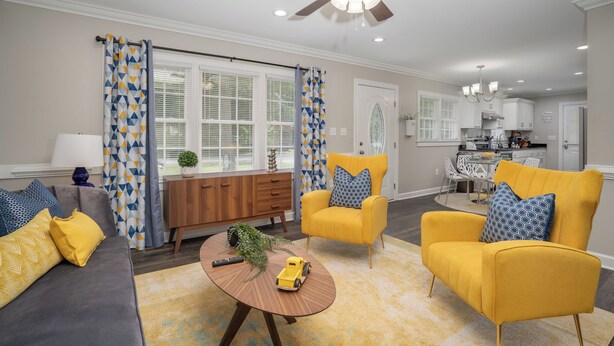 A living room with a sofa, yellow armchairs, a coffee table, and a ceiling fan. - Modern Home In PRIME location - King Bed/ Spacious

 (Rocky Mount)