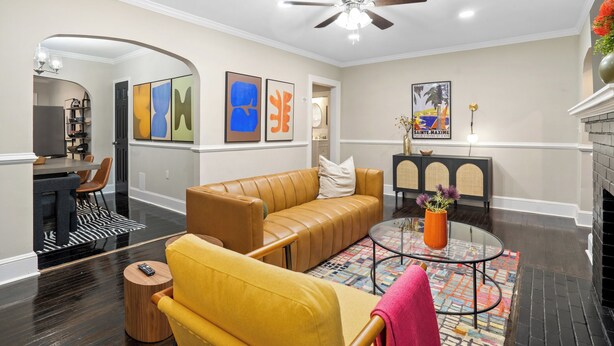 A modern living room with a leather sofa, a yellow armchair, a glass coffee table, and a fireplace.