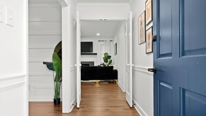 A hallway with a blue door, white walls, and a wooden floor.