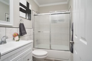 Ein modernes Badezimmer mit einer Duschkabine, einer weißen Toilette und einem Waschbecken mit Blumen in einer Vase.