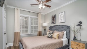 Une chambre à coucher avec un lit, une table de chevet, une lampe et un ventilateur de plafond.