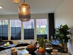 Ein Essbereich mit Tisch, gedeckt für ein Frühstück, inklusive Brot, Obst und einem Glas Saft.