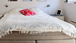 A bedroom with a large bed, a red floral pillow, a white knitted blanket, and three framed pictures on the wall. - 7 Person Holiday Home in Vesteroy-by Traum (Hvaler)
