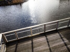 Eine Holzstege, der sich über ruhiges Wasser erstreckt, mit einem Metallgeländer am Rand.