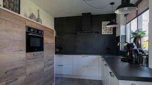 Een moderne keuken met een inbouwoven, koffiezetapparaat en een groot raam met uitzicht.