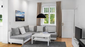 Ett modernt vardagsrum med en grå soffa, ett vitt soffbord och en tv.