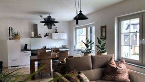 Ein modernes Wohnzimmer mit einer Couch, Essbereich und Küche.