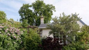 Een huis met een tuin, een houten pergola en een schoorsteen.