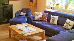 A cozy living room with a blue sofa set, a wooden coffee table, and a bookshelf. - Tonnihuus Comfortable Holiday Residence (Toenning)