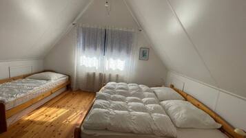 Habitación tipo dormitorio con dos camas individuales y una cama más grande.