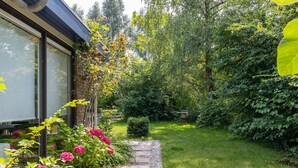 A garden pathway leading to a house with a brick wall and large windows. - Welcoming Family Home (Wolphaartsdijk)